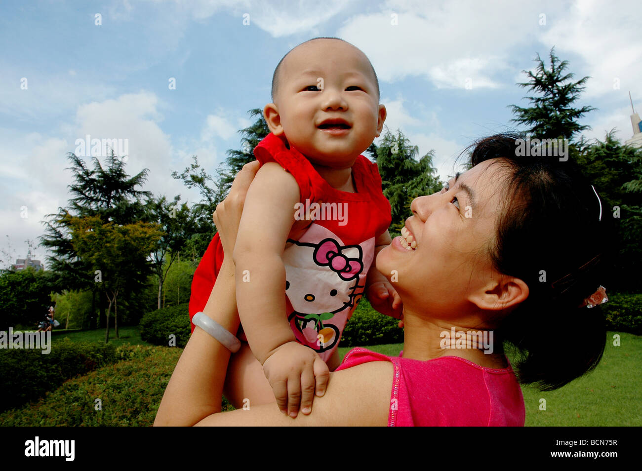 I giovani cinesi madre tenendo il suo bambino nel parco, Shanghai, Cina Foto Stock