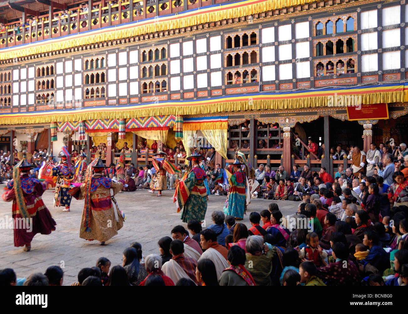 I monaci, persone locali e turisti guarda black hat ballerini presso il festival Trashigang, tsechu. Trashigang Dzong, Bhutan Foto Stock