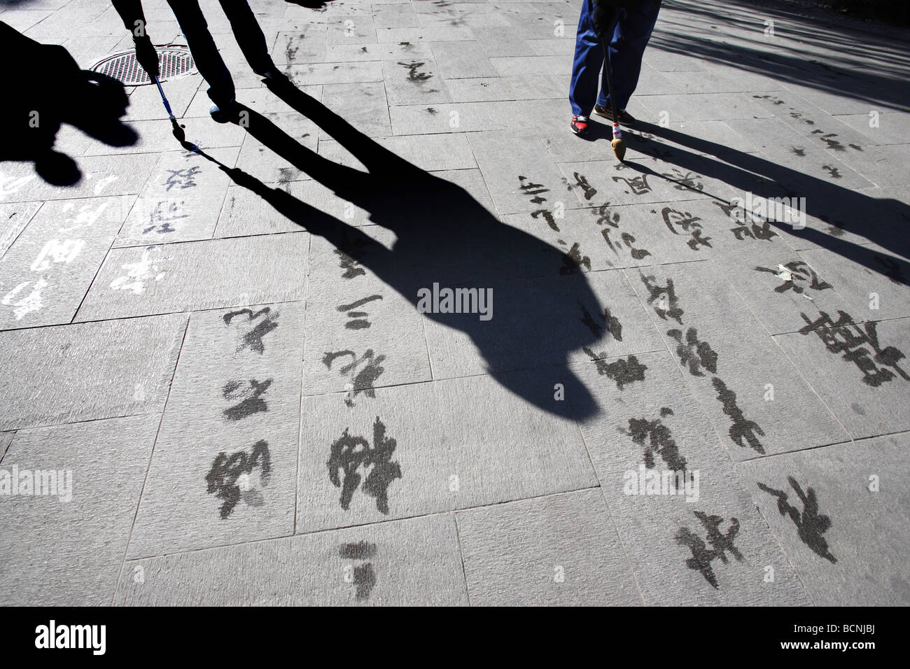 Dilettante locale calligrafo calligrafia pratica con punta in gomma spazzola e acqua sulla massa di cemento come una forma di esercizio, Foto Stock