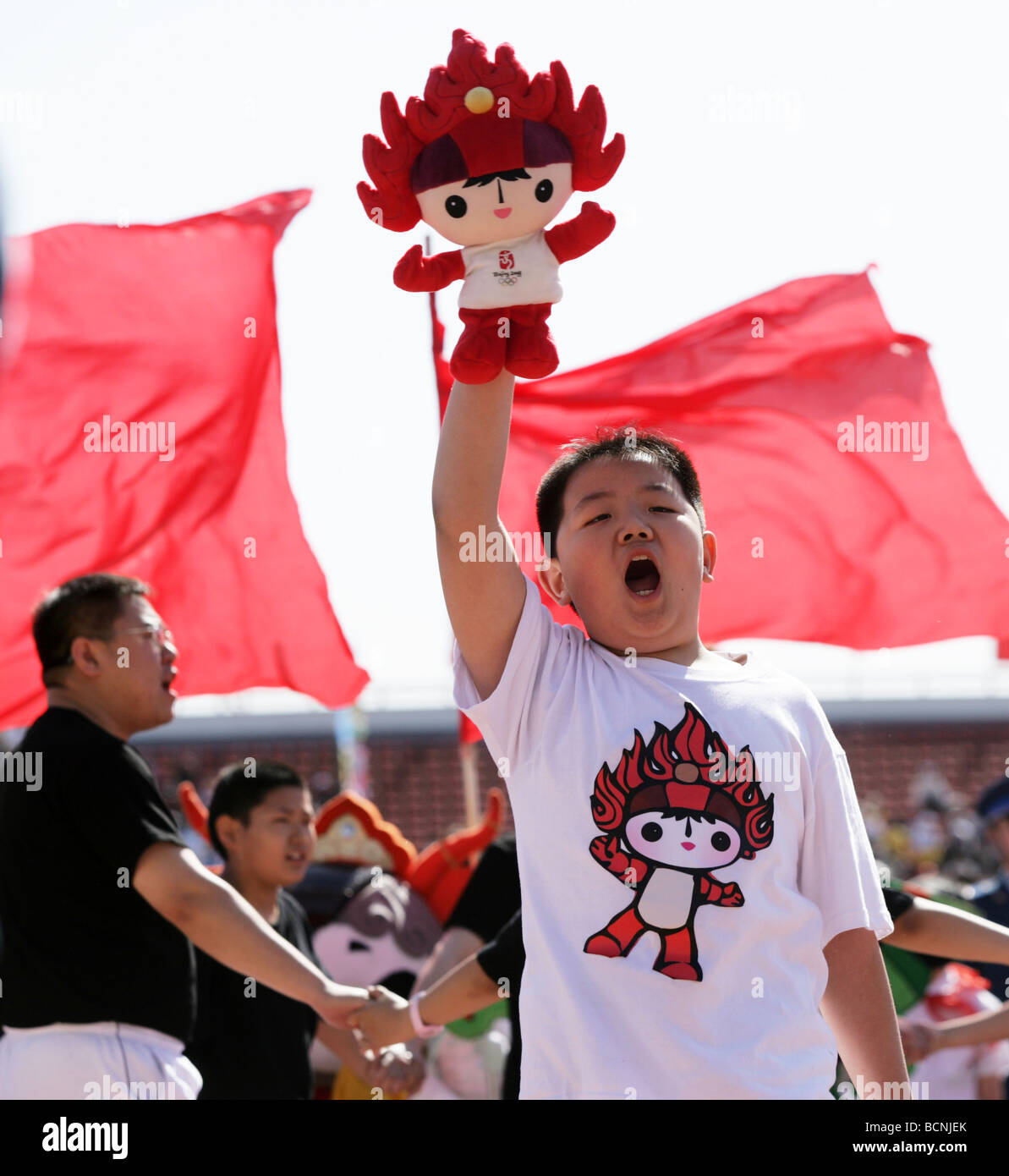 Ragazzo in Fuwa T-shirt holding Fuwa bambola durante la visione di un gioco sportivo a Pechino, Cina Foto Stock