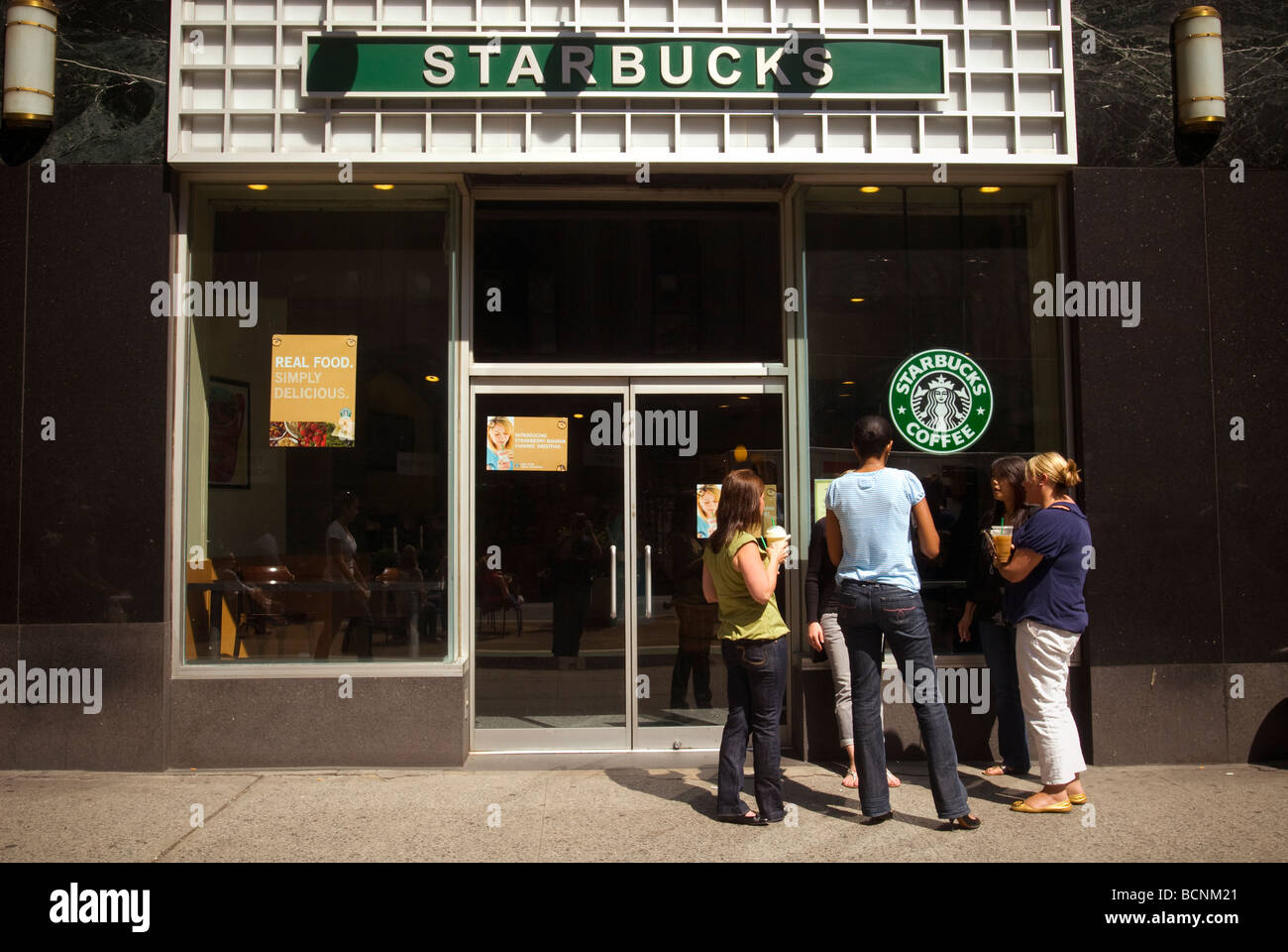 I clienti di Starbucks godersi una tazza di caffè al di fuori di un Starbucks Coffee shop in New York Foto Stock