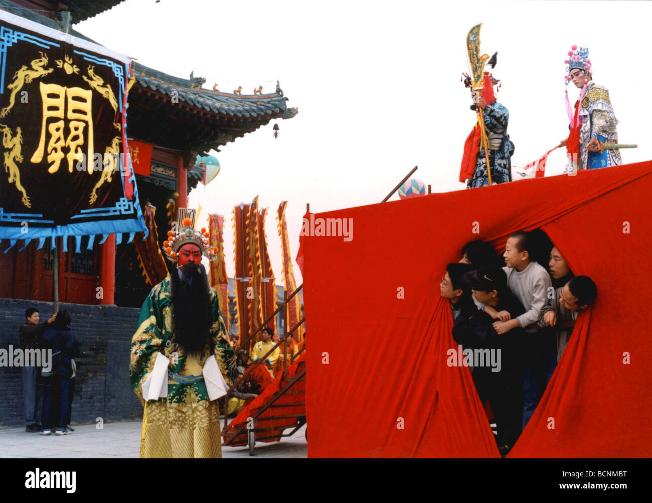 Ragazzi guardando un attore di opera in piena customer da sotto il palcoscenico di Henan Opera prestazioni, nella provincia di Henan, Cina Foto Stock
