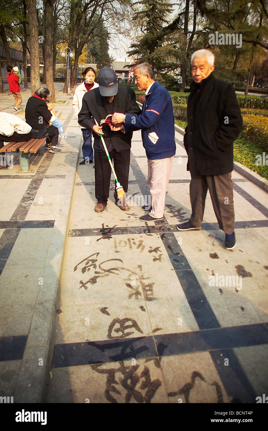 Anziani uomini cinesi praticare la calligrafia utilizzando inchiostro di grandi dimensioni pennello e acqua del terreno, Pechino, Cina Foto Stock