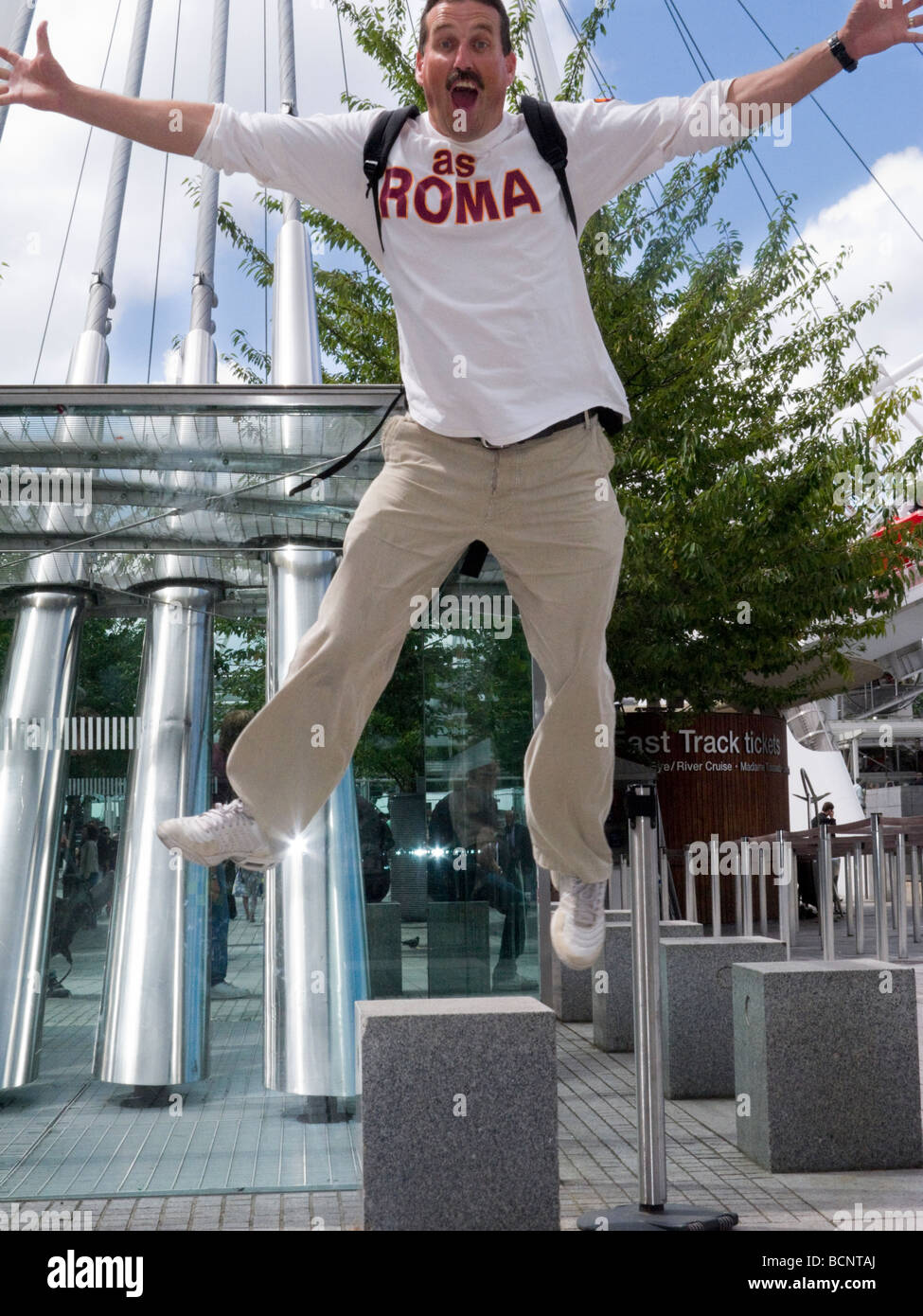 Tourist indossando un AC Roma team football shirt salti di gioia, di Londra vicino al Millennium wheel. Regno Unito Foto Stock