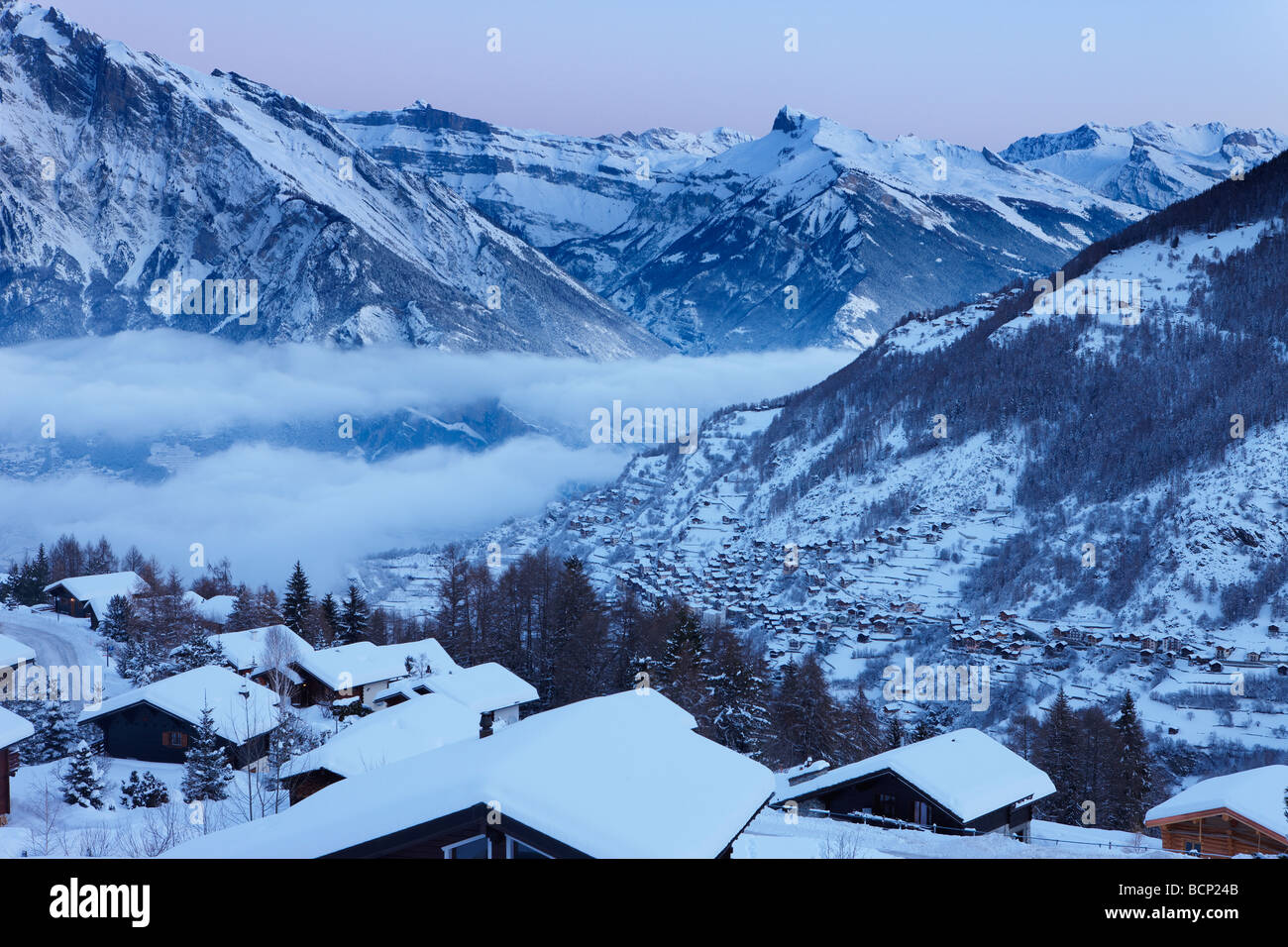 Una leggera nevicata fresca sul villaggio alpino di La Tzoumas all'alba, con Iserables e la Valle del Rodano al di là, Vallese, Svizzera Foto Stock
