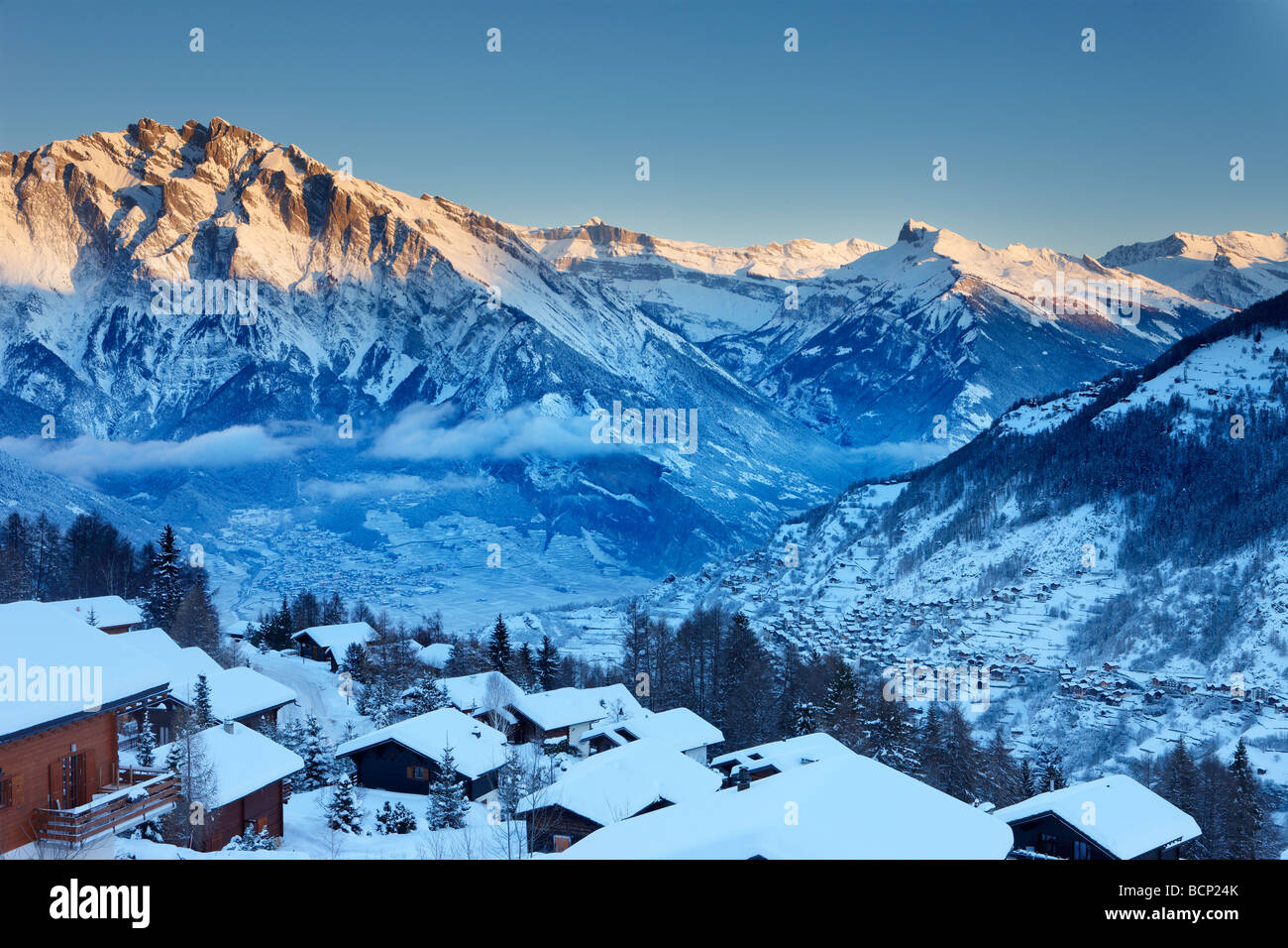 Una leggera nevicata fresca sul villaggio alpino di La Tzoumas all'alba, con Iserables e la Valle del Rodano al di là, Vallese, Svizzera Foto Stock