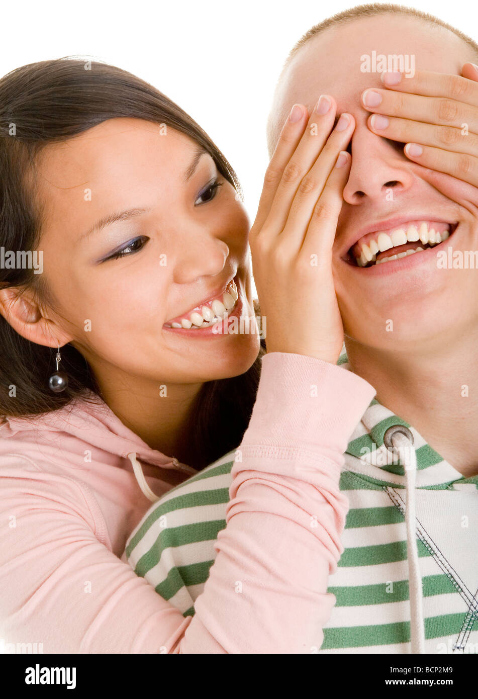 Junge asiatische Frau hält ihrem Freund von hinten die Augen zu Foto Stock