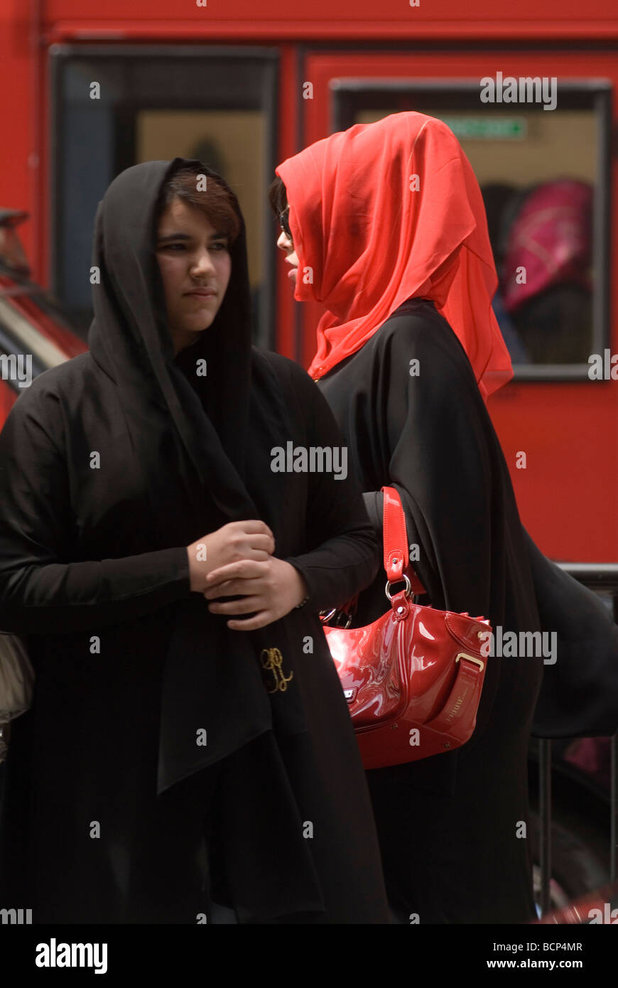 Ricche donne musulmane Londra. Indossa un tradizionale Abaya nero, un colorato Hijab rosso. Turisti arabi del Medio Oriente Knightsbridge fa shopping nel Regno Unito anni '2009 2000 Foto Stock