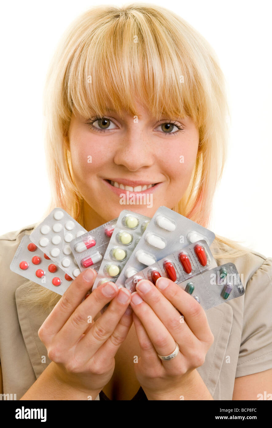 Junge Frau hält lachend verschiedene Medikamente in mano ihrer Foto Stock