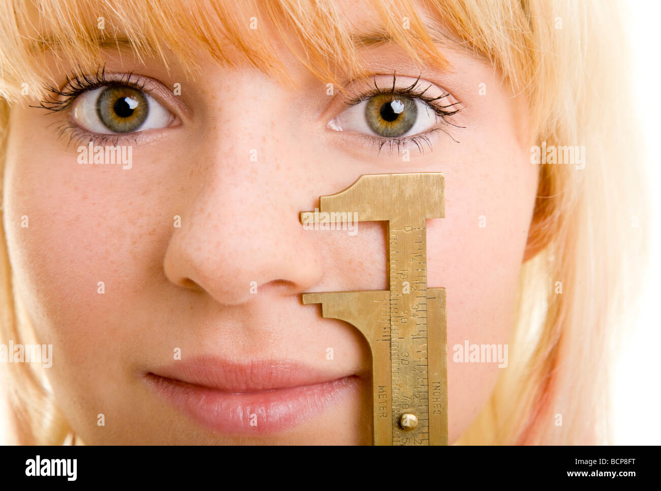 Junge blonde Frau hält sich eine Schublehre un ihre Nase Foto Stock