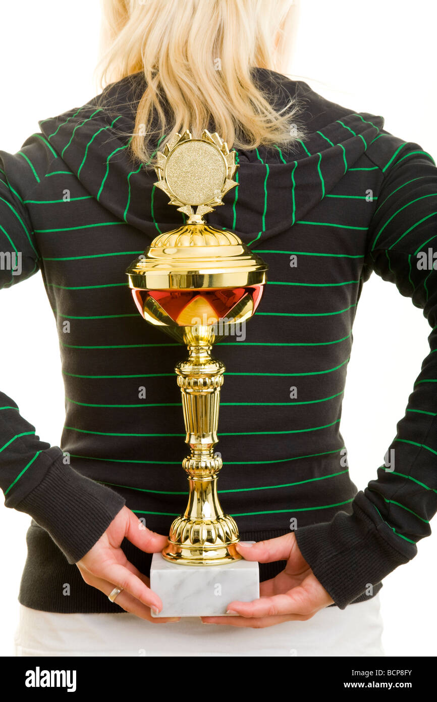 Junge Frau in Sportkleidung hält einen Pokal hinter ihrem Rücken versteckt Foto Stock