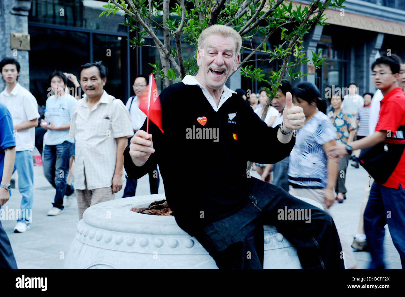 Turismo caucasici con la bandiera nazionale cinese in mano in posa per fotocamera, Giochi Olimpici di Pechino 2008, Pechino, Cina Foto Stock