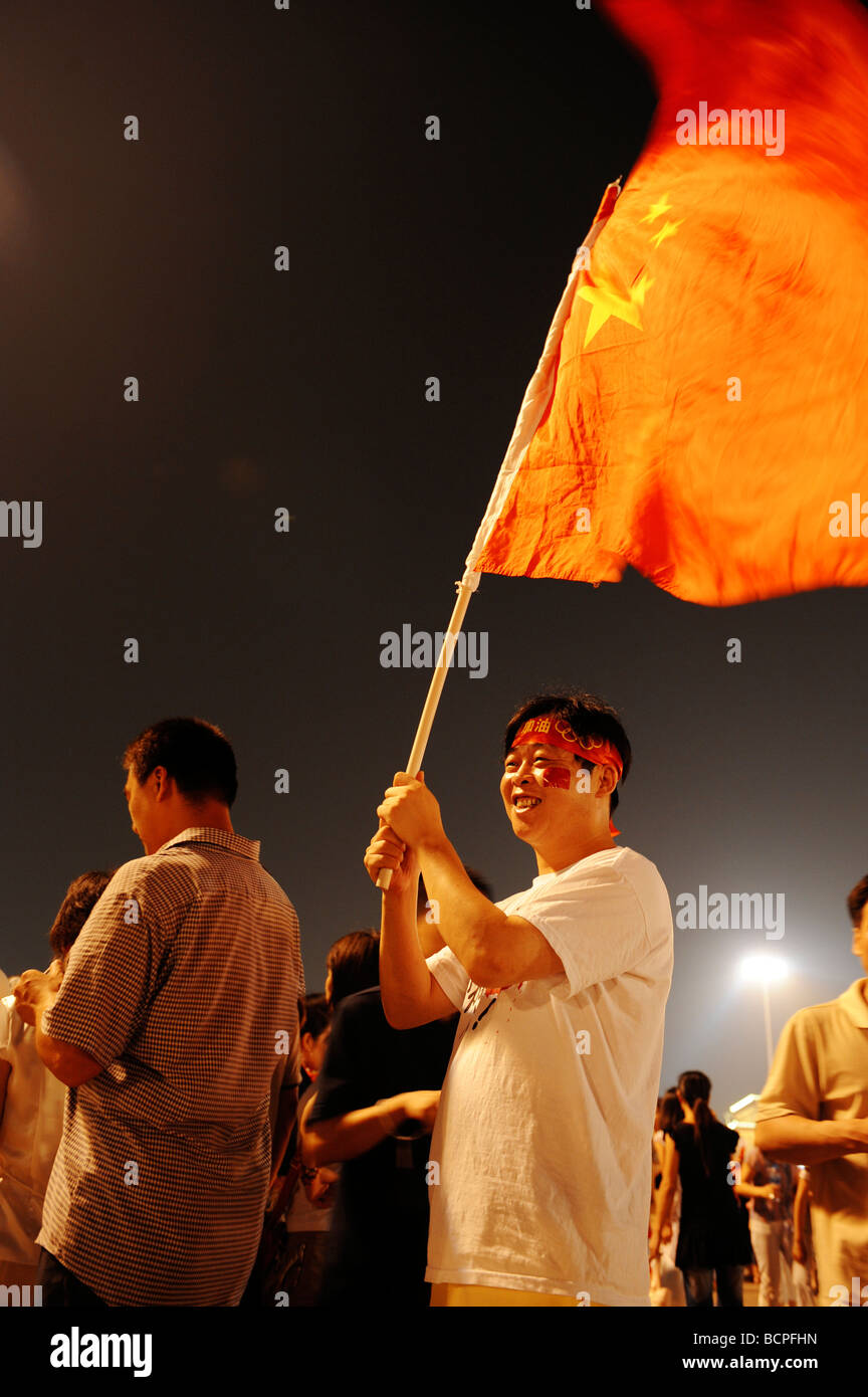 Uomo cinese tenere bandiera nazionale cinese in Piazza Tian An Men di notte Durante Pechino 2008 Giochi olimpici a Pechino, Cina Foto Stock