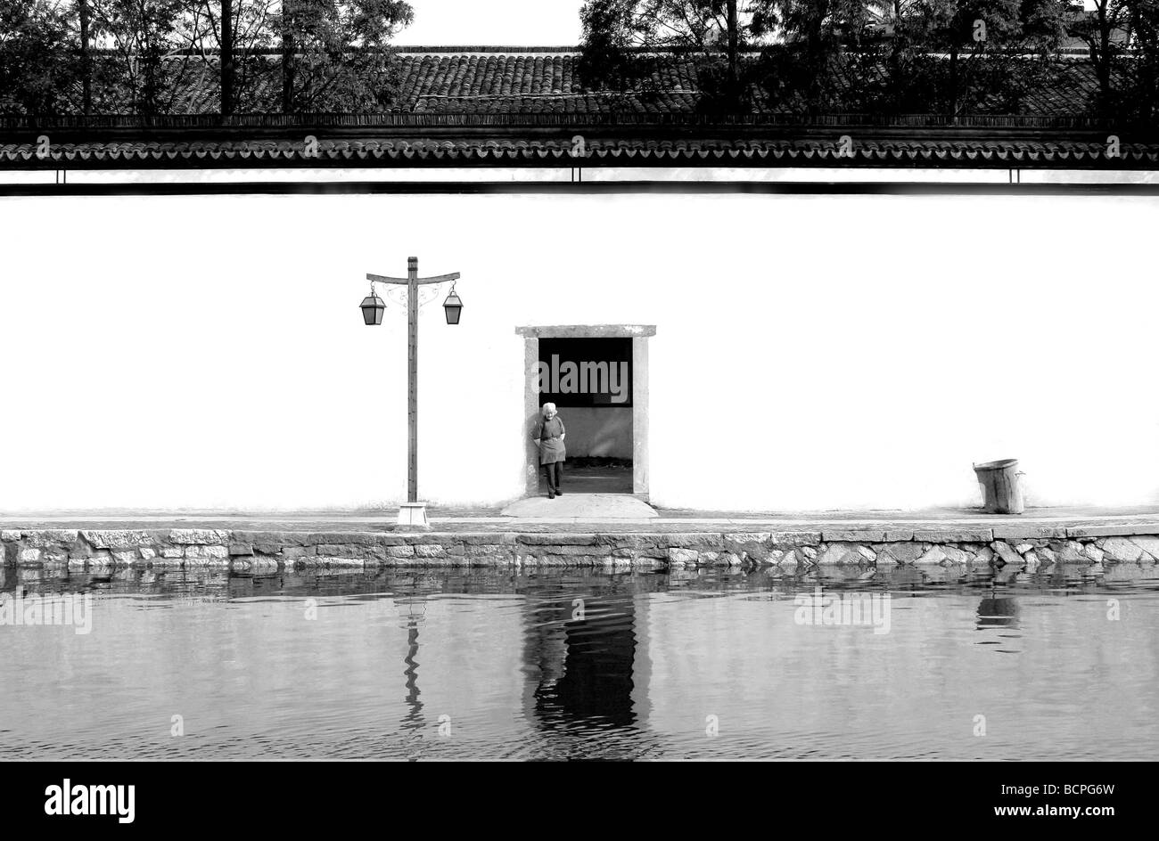 Donna anziana in piedi la porta della tradizionale mansion, Xitang città d'acqua, nella provincia di Zhejiang, Cina Foto Stock