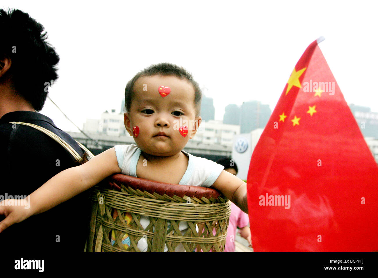 Chinese baby boy sventola bandiera cinese nel suo padre il paniere di saluti 2008 Pechino torcia olimpica, Chengdu Sichuan Foto Stock