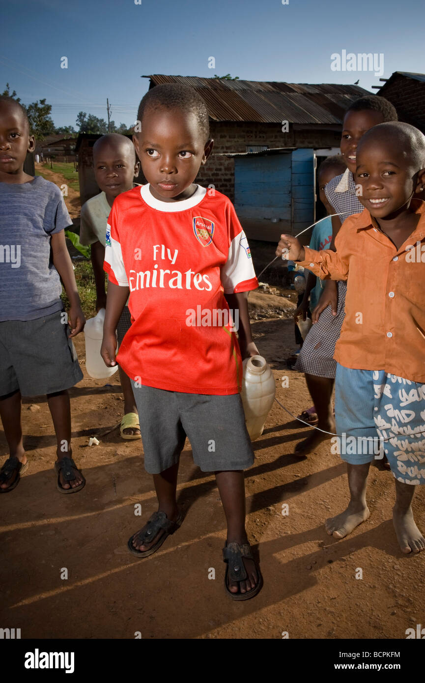 Giovane ragazzo in Arsenal Football Club shirt su strade in baraccopoli ugandese Foto Stock