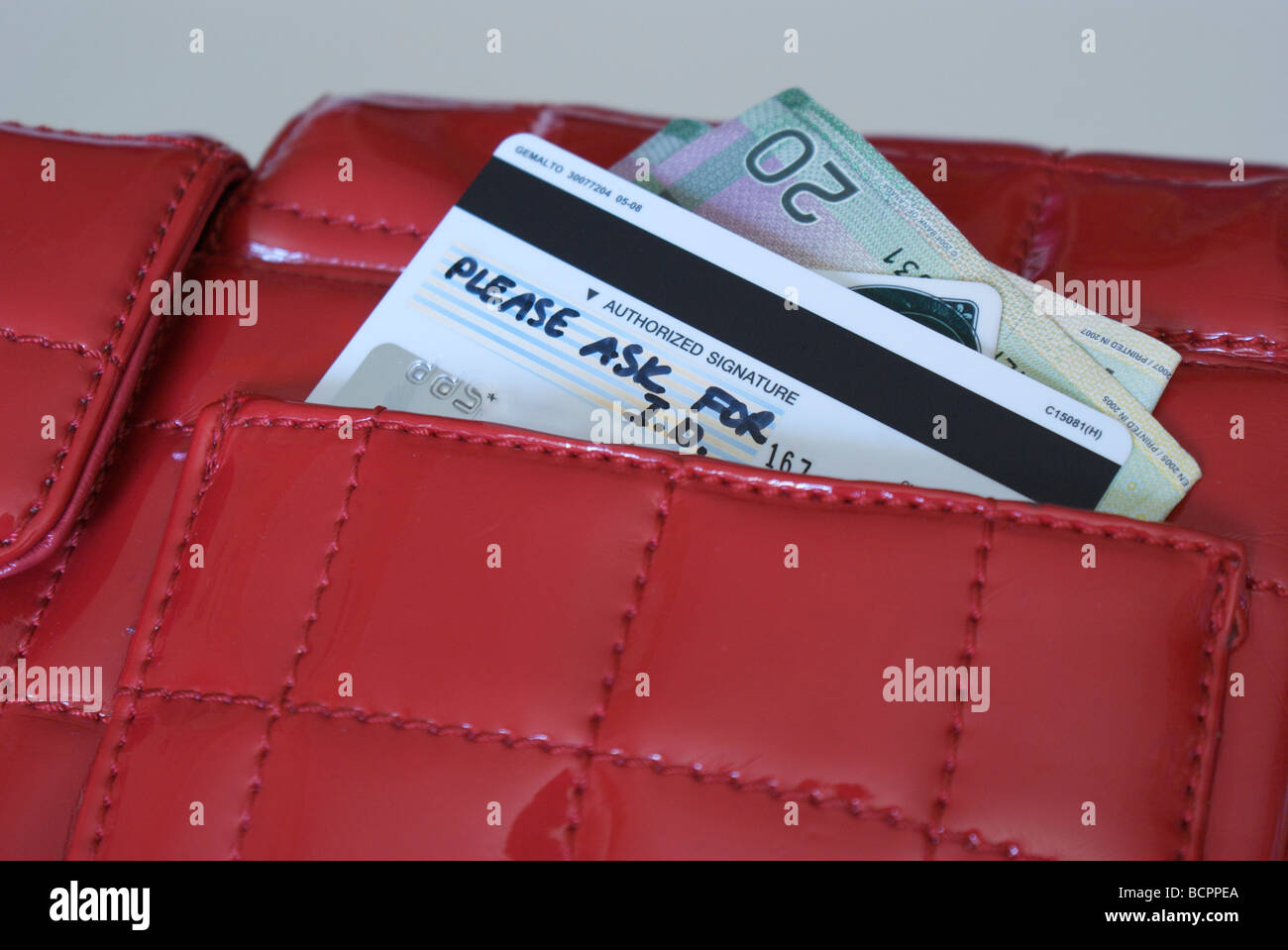 In contanti e con carta di credito che spuntavano di un portamonete rosso. Foto Stock