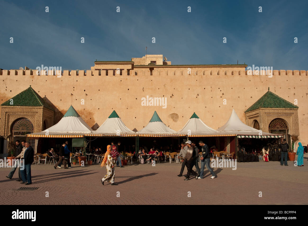 Locali marocchine passando per le antiche mura della medina di Meknes, Marocco nel sole del tardo pomeriggio Foto Stock