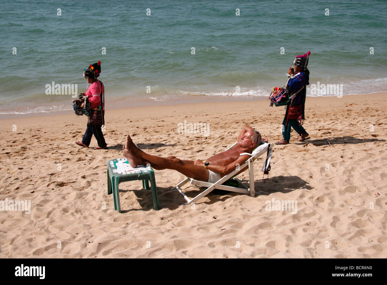 Maschio di relax sulla spiaggia spiaggia di Pattaya in Thailandia con i venditori sulla spiaggia Foto Stock