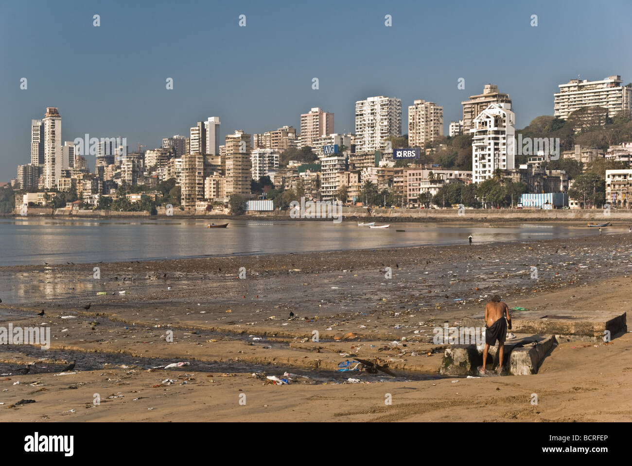 Una persona senza dimora lavaggio sulla spiaggia di Mumbai Foto Stock