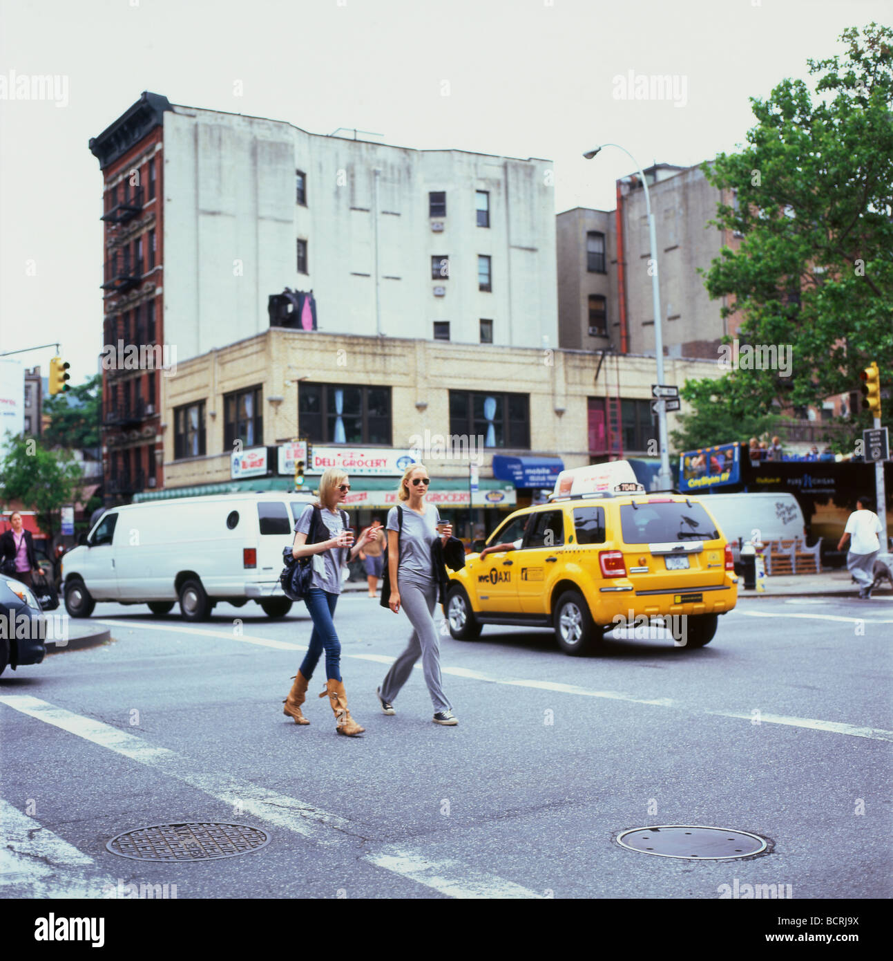 Giovani donne amici pedonale a piedi attraverso crosswalk Lower East Side di New York City NY Manhattan KATHY DEWITT Foto Stock