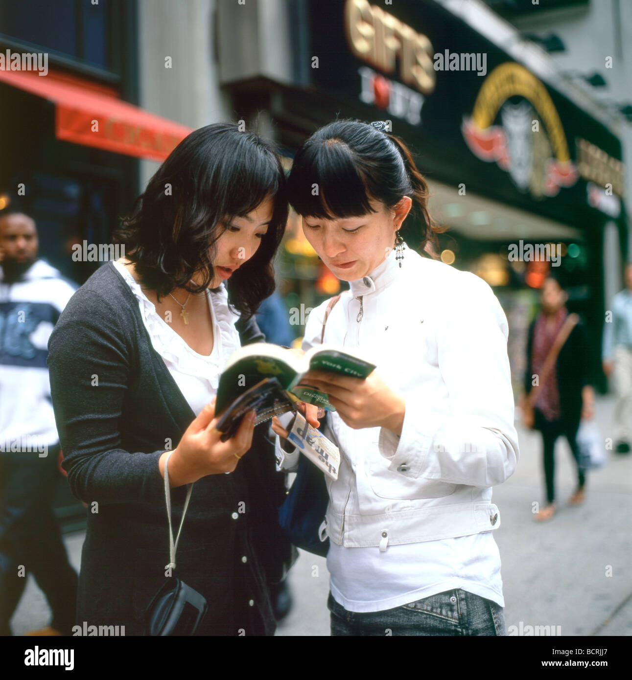 Giovani donne asiatiche turisti che cercano una guida e una mappa di New York sulla 5th Avenue a New York City NY USA Stati Uniti d'America KATHY DEWITT Foto Stock