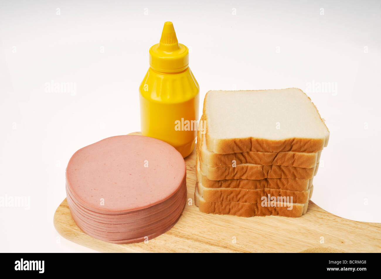 Ingredienti per il sandwich di bologna con senape e pane bianco impilati su un legno tagliere. Foto Stock