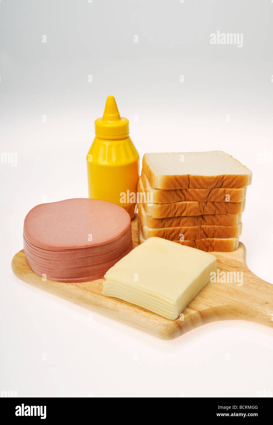Ingredienti per una bologna e sandwich di formaggio con la pila di salumi, formaggio, pane e senape sul pannello di legno Foto Stock