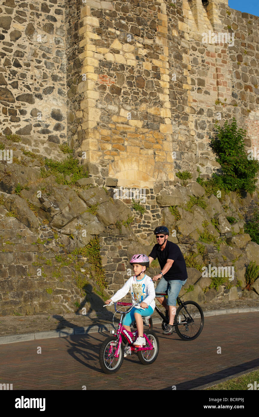 Castello di Carrickfergus con un padre e figlia in bicicletta intorno alla base del castello nella contea di Antrim Irlanda del Nord Foto Stock