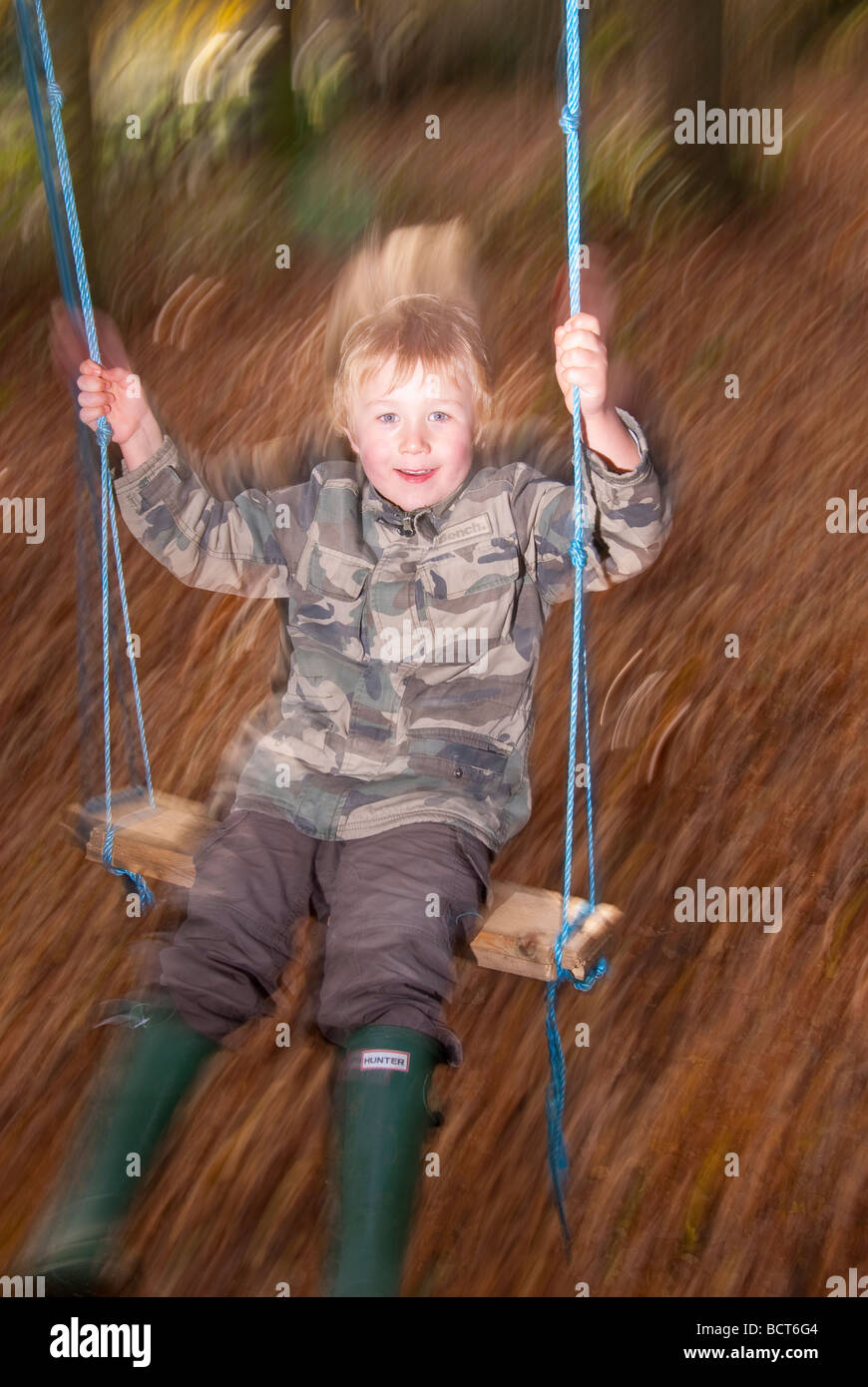 Un bambino di cinque anni, ragazzo su un altalena che mostra il movimento utilizzando la sincronizzazione con la tendina posteriore metodo flash nel Regno Unito Foto Stock