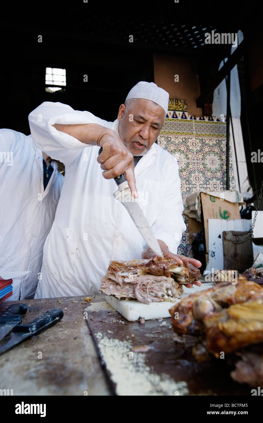 L'uomo vendita di deliziosi piatti a base di carne di agnello in un vicolo del mercato (souk o souq) nella città vecchia (a) Medina di Marrakech, Marocco. Foto Stock