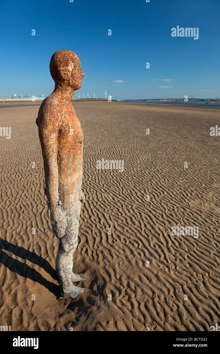 Sir Antony Gormley artwork in altro luogo si trova sulla spiaggia di Crosby che forma parte della costa di Sefton, entro il Liverpool City regione del Regno Unito. Foto Stock