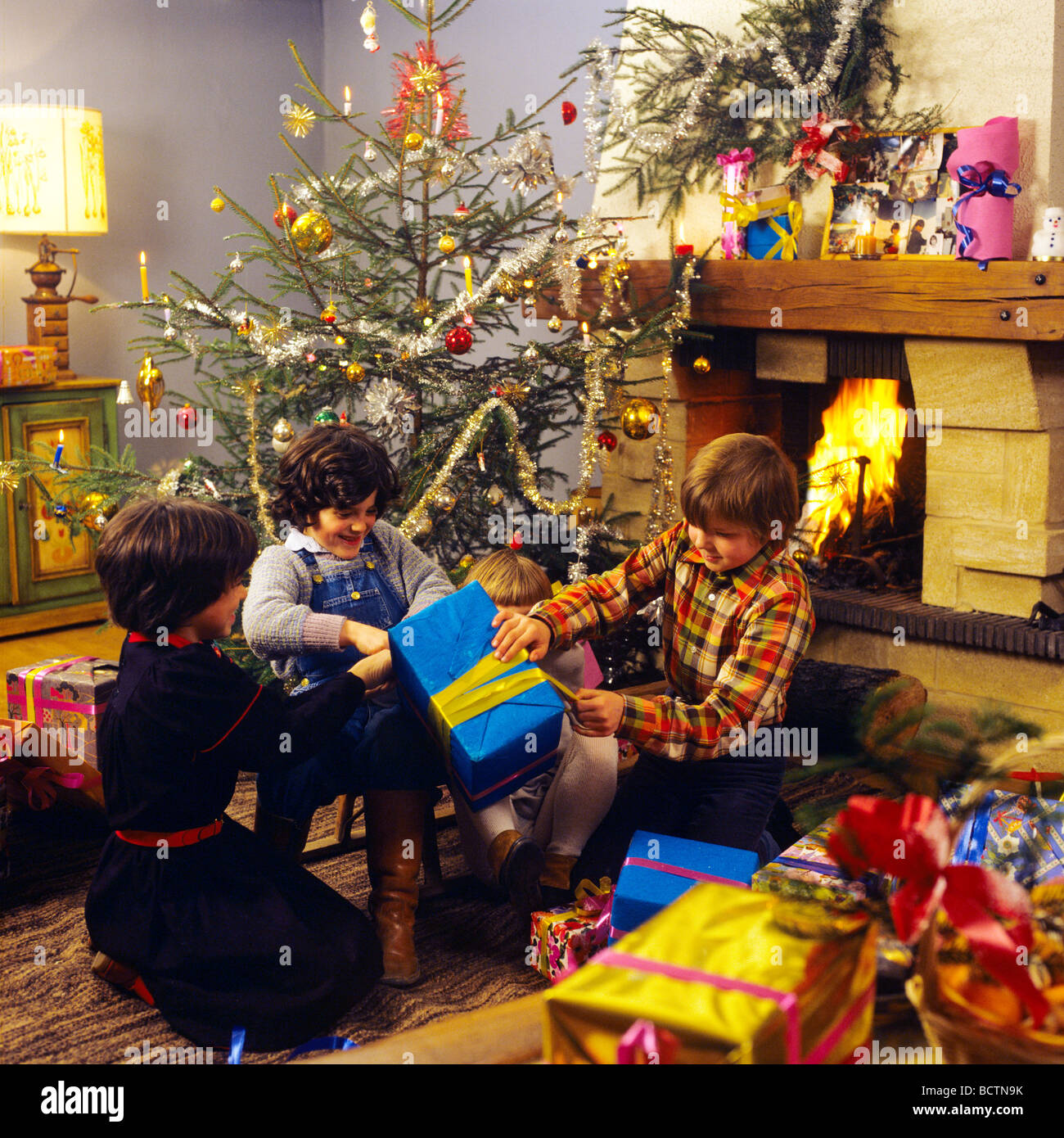 3 Figli di aprire i regali di Natale sotto l'albero di Natale di famiglia  presenta apertura ad albero Foto stock - Alamy