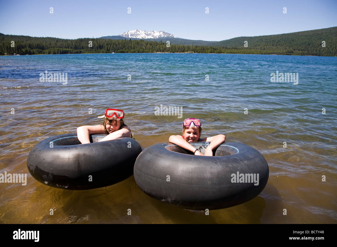 Due teen agers galleggiante in tubi interni in Crescent Lake durante l'estate in montagna a cascata di Oregon centrale Foto Stock