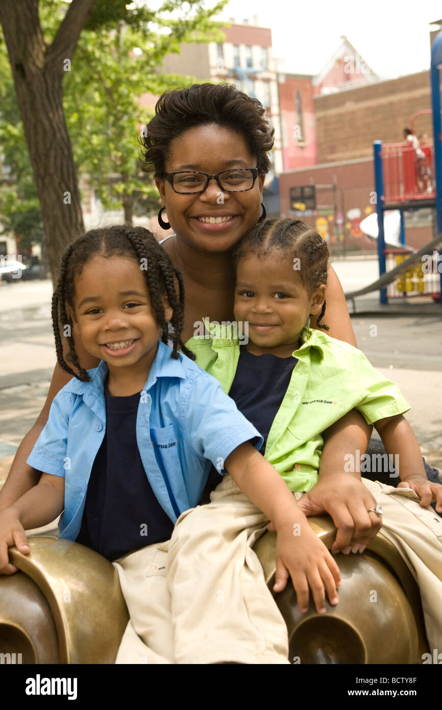 Madre single con i suoi due bambini in un parco giochi a New York City Foto Stock