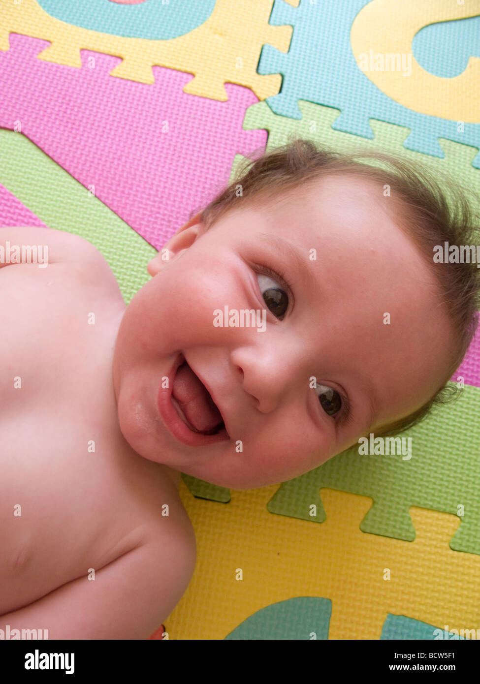 Sei mese baby giocare felicemente giocando sui tappeti colorati Foto Stock