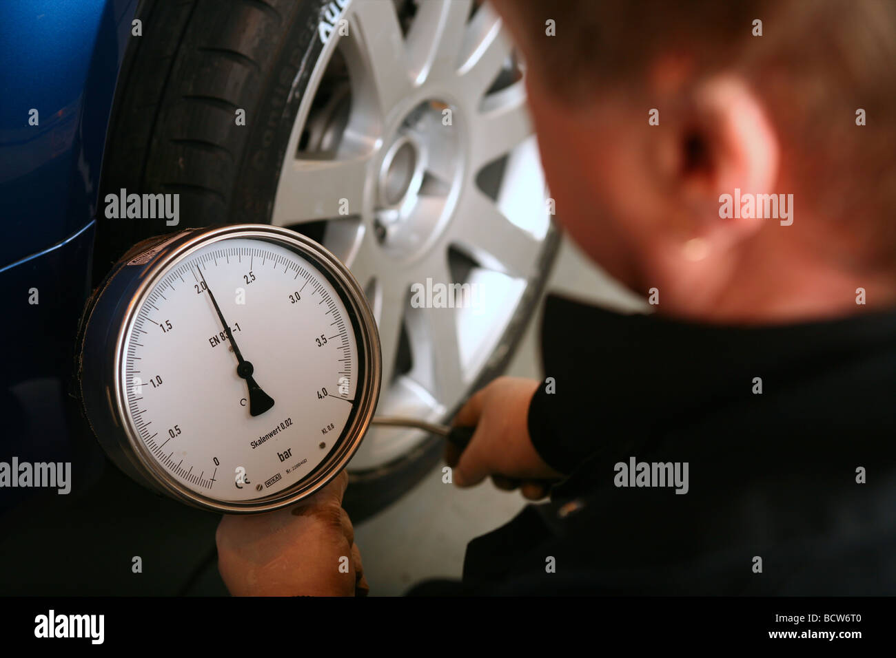 Un meccanico di controllo della pressione dei pneumatici su una vettura Foto Stock