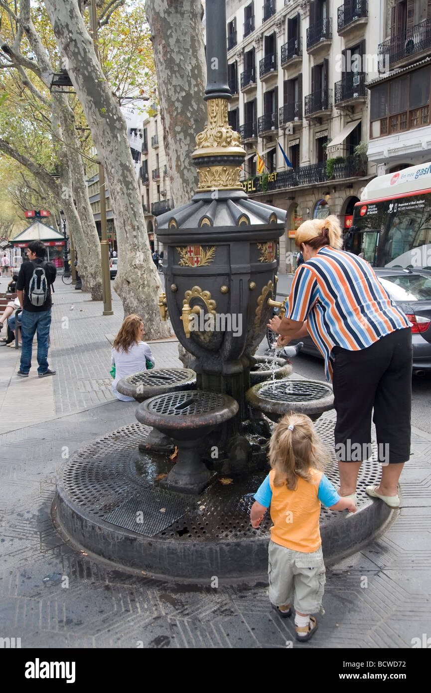 Las Ramblas donna e bambino prendendo l'acqua da una fontana Barcellona Catalonia Spagna Foto Stock