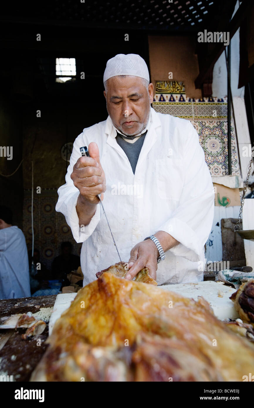 L'uomo vendita di deliziosi piatti a base di carne di agnello in un vicolo del mercato (souk o souq) nella città vecchia (a) Medina di Marrakech, Marocco. Foto Stock