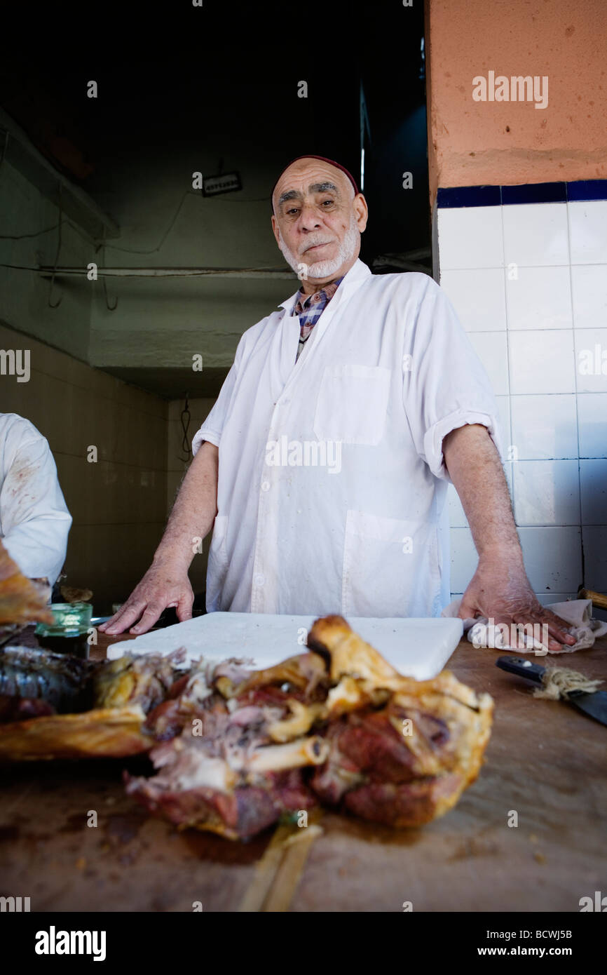L'uomo vendita di deliziosi piatti a base di carne di agnello in un vicolo del mercato (souk o souq) nella città vecchia (a) Medina di Marrakech, Marocco. Foto Stock