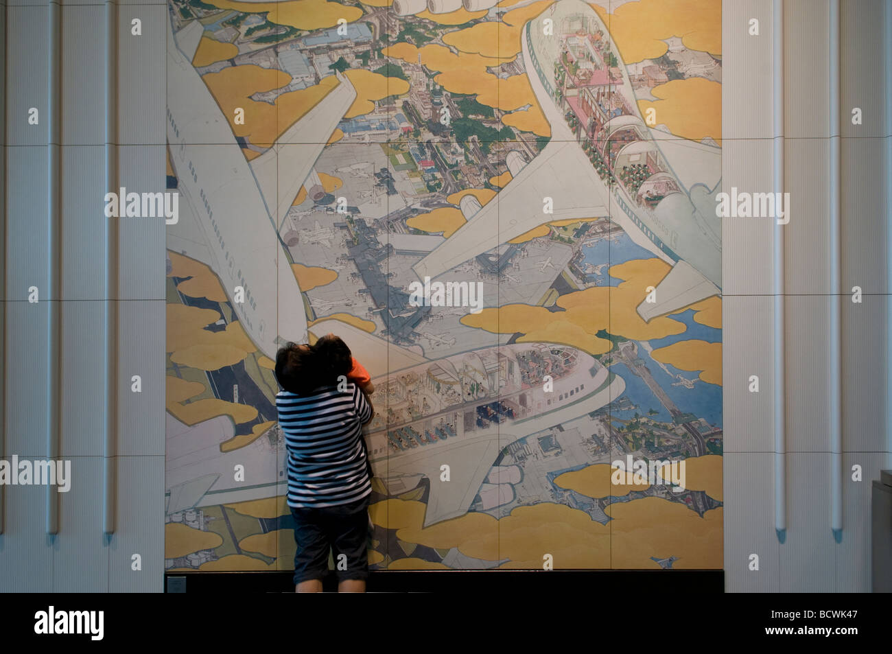 Un giovane ragazzo con suo padre guardando a pannelli di ceramica murale intitolato "Occupato Ala Sud' da Akira Yamaguchi nel Terminal 1 Aeroporto di Narita Tokyo Giappone Foto Stock