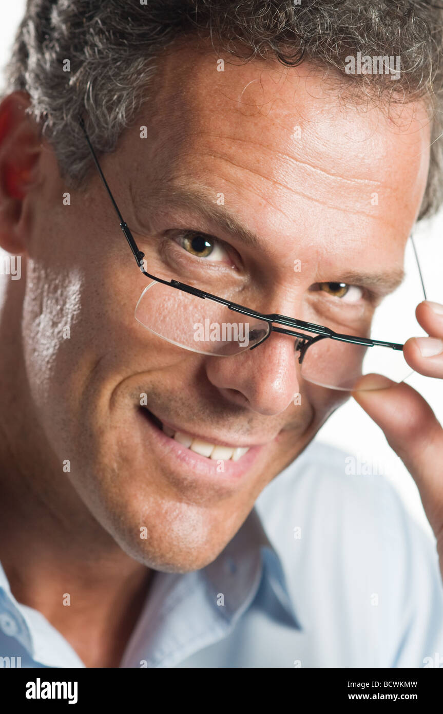 Uomo maturo con gli occhiali sorridente e guardando la telecamera attraverso un paio di occhiali Foto Stock