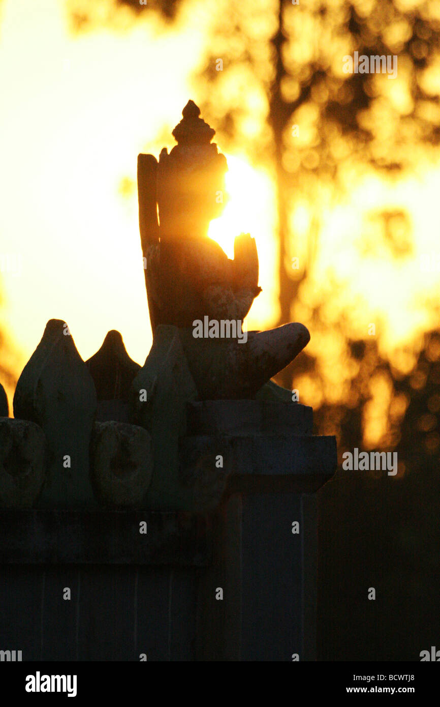 L'albe oltre la statua di orante di una statua indù in India. Le staue si stagliano dal golden sun. Foto Stock