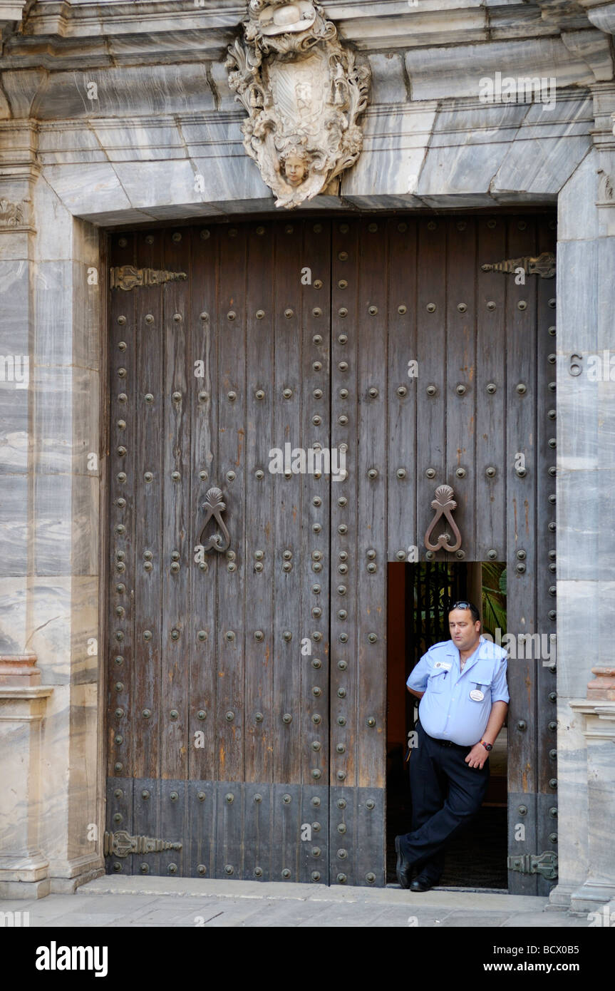 Grande pesante porta di legno con cornice in marmo e la guardia di sicurezza Plaza del Obispo Malaga Spagna Foto Stock