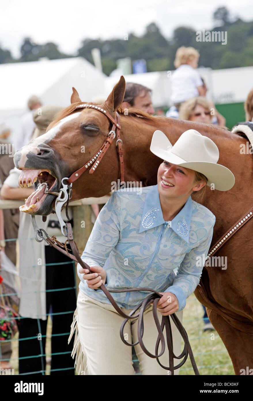 Attraente giovane donna tenendo un cavallo, con il cavallo "miling' alla fotocamera Foto Stock