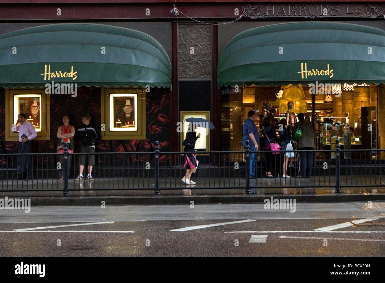 La gente si ripara dalla pioggia al di fuori di Harrods Foto Stock
