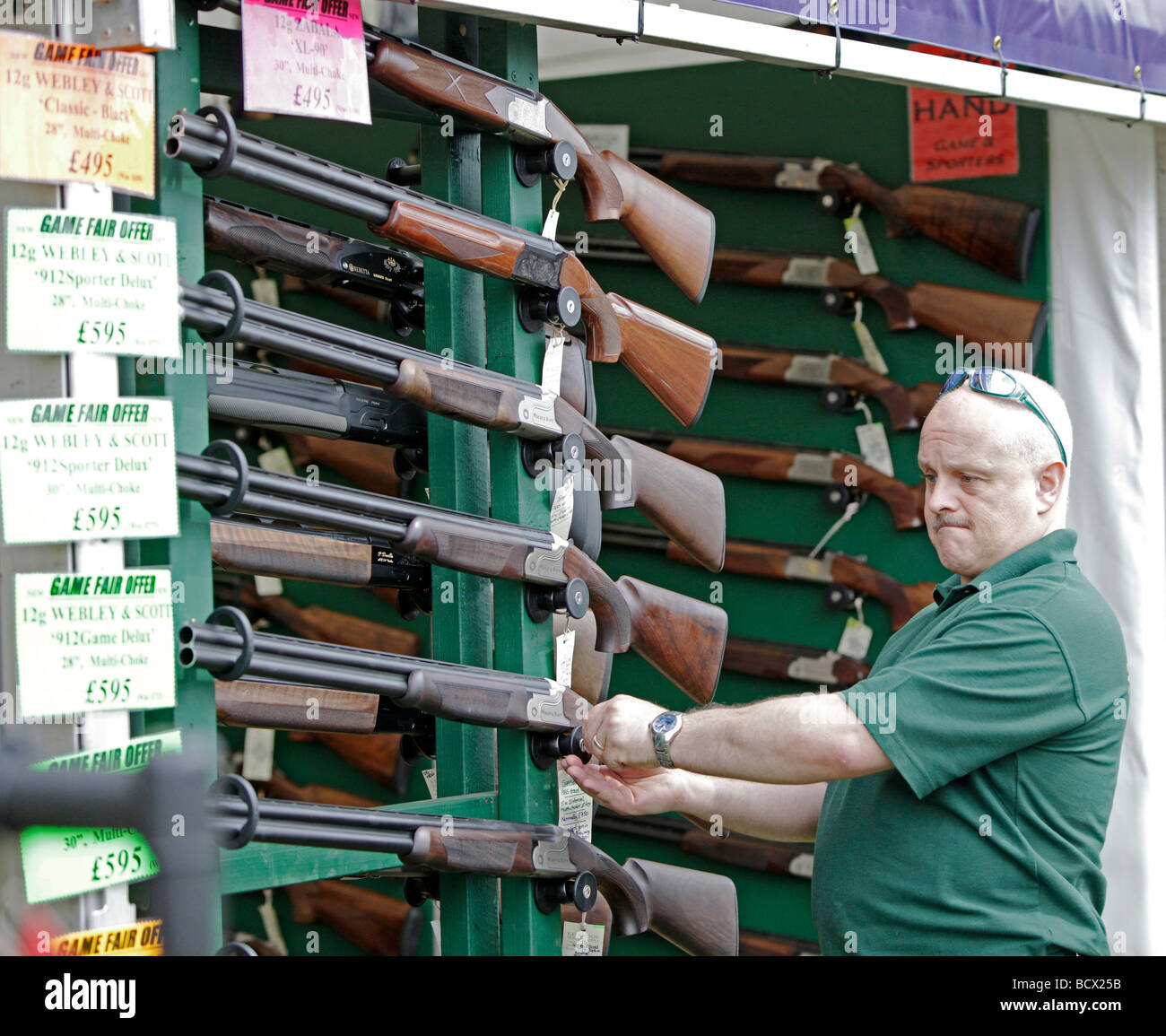 Un cliente checking out fucili a canna liscia sul display in un paese Fiera degli Sport event Foto Stock