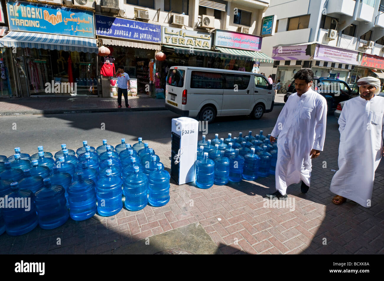 Gli uomini a piedi nella parte anteriore di acqua imbottigliata in Deira Dubai Foto Stock