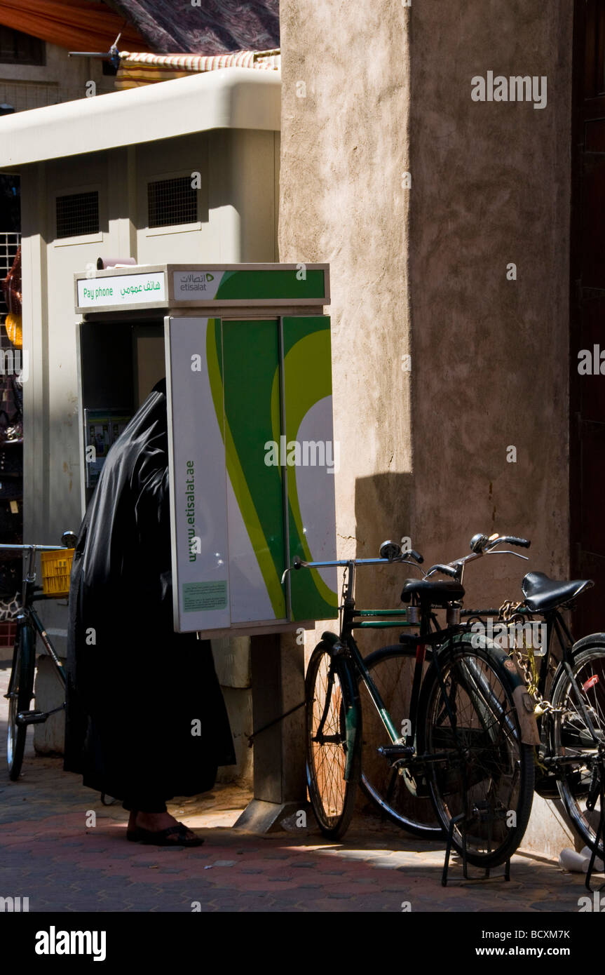Donna velata a parlare su un telefono pubblico Bur Dubai di Dubai di settore Foto Stock