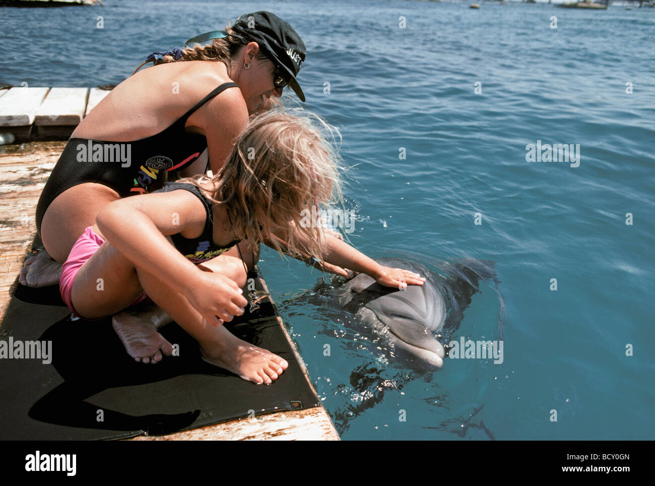 Bambino autistico terapia interagendo con dolphin trainer e Bottlenose Dolphin Foto Stock